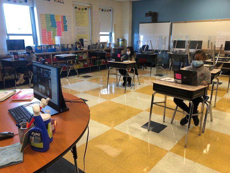 At Miles Davis Magnet Academy in Chicago, a teacher juggles simultaneous instruction in a classroom where some fourth graders are learning in person and others are learning remotely.