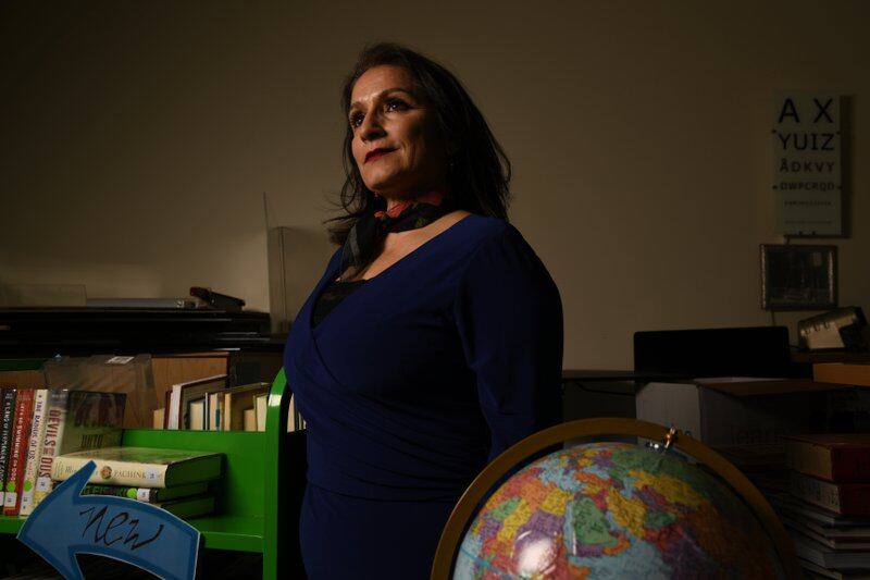 Susana Cordova stands in a library with a globe.