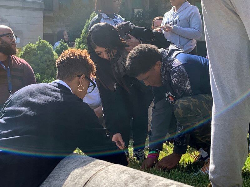 An outdoor shot of several people bending over to plant flowers in a grassy area