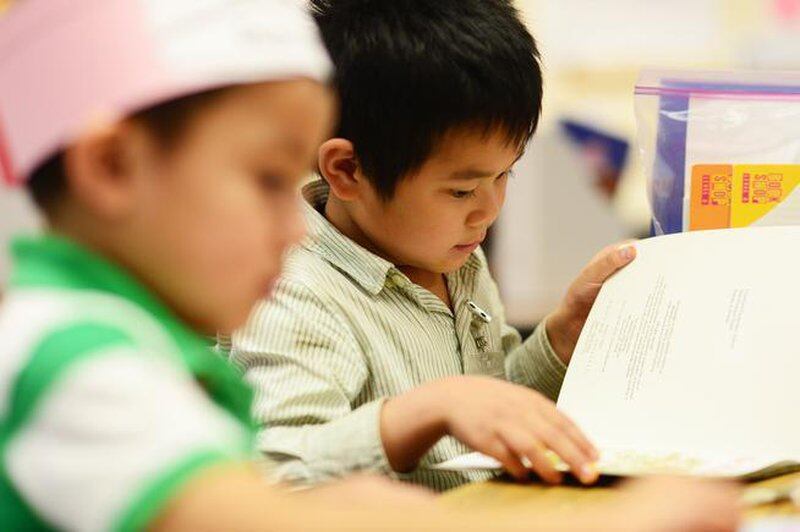 A kindergartner flips the page while reading in class at Crawford Elementary in Aurora.