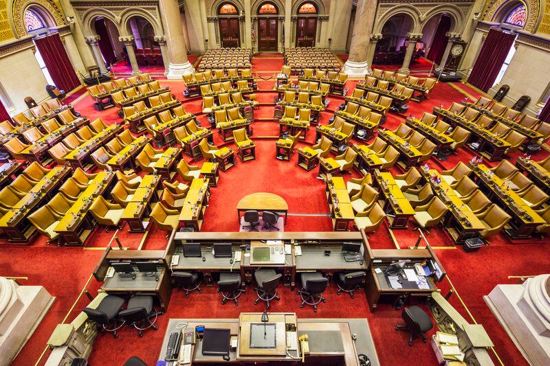 An overhead view of the NY Assembly room with red carpets and rows of yellow chairs