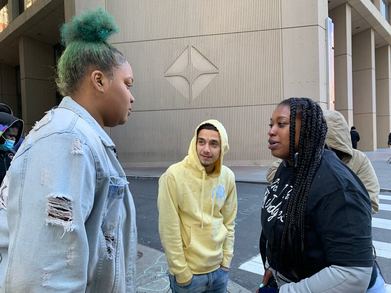 Three young people talking in front of a crosswalk