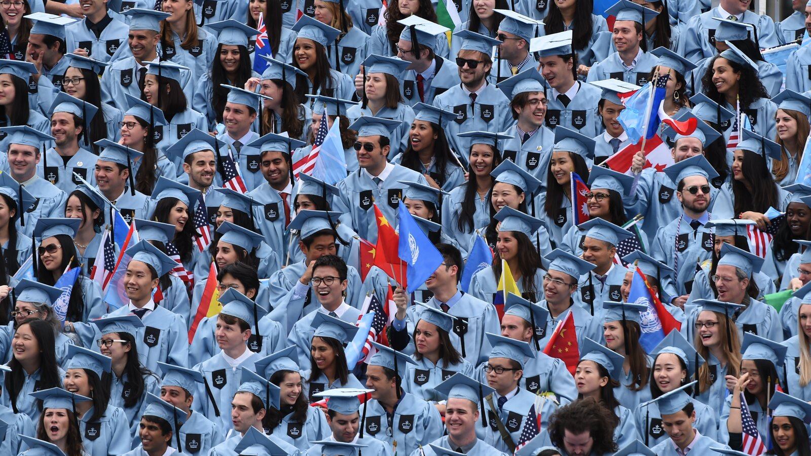 Columbia University graduates wear blue graduation robes and caps.