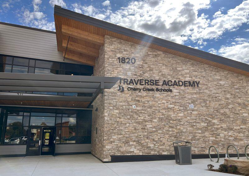 The exterior and entrance to a building with a brown brick face, marked “Traverse Academy”