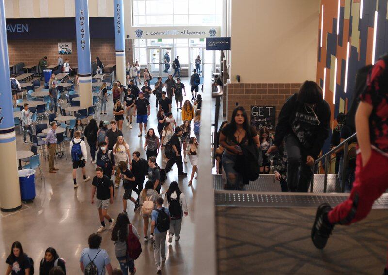 High school students walk up stairs in a hallway during a passing period between classes.