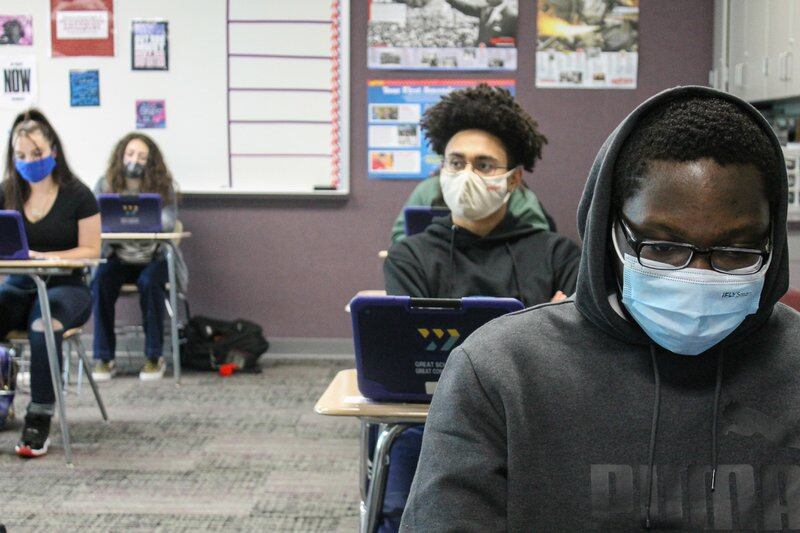 Four masked students sit at desks and look into laptops at Ben Davis High School in Indianapolis, Ind. on Friday, April 9, 2021.