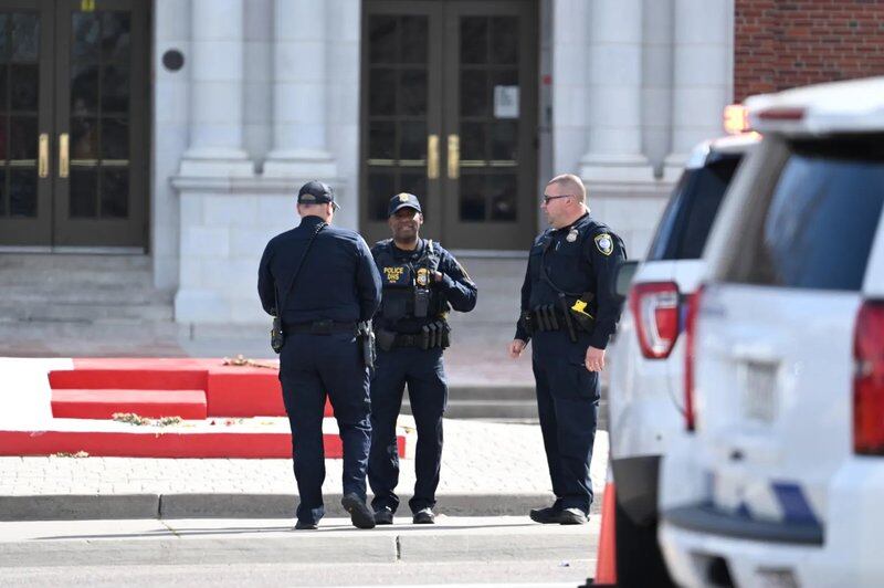 Three police officers stand in front of steps of East High School in Denver, Colorado, after a shooting there on March 22, 2023.