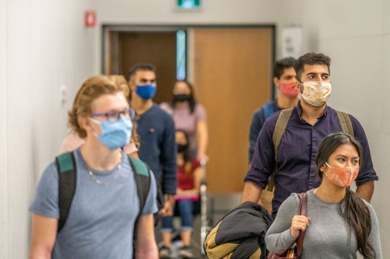 Students filing into class while wearing protective face masks.