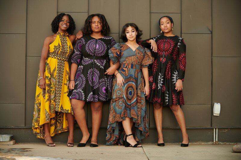 Four Denver students in bold print dresses pose for a portrait.