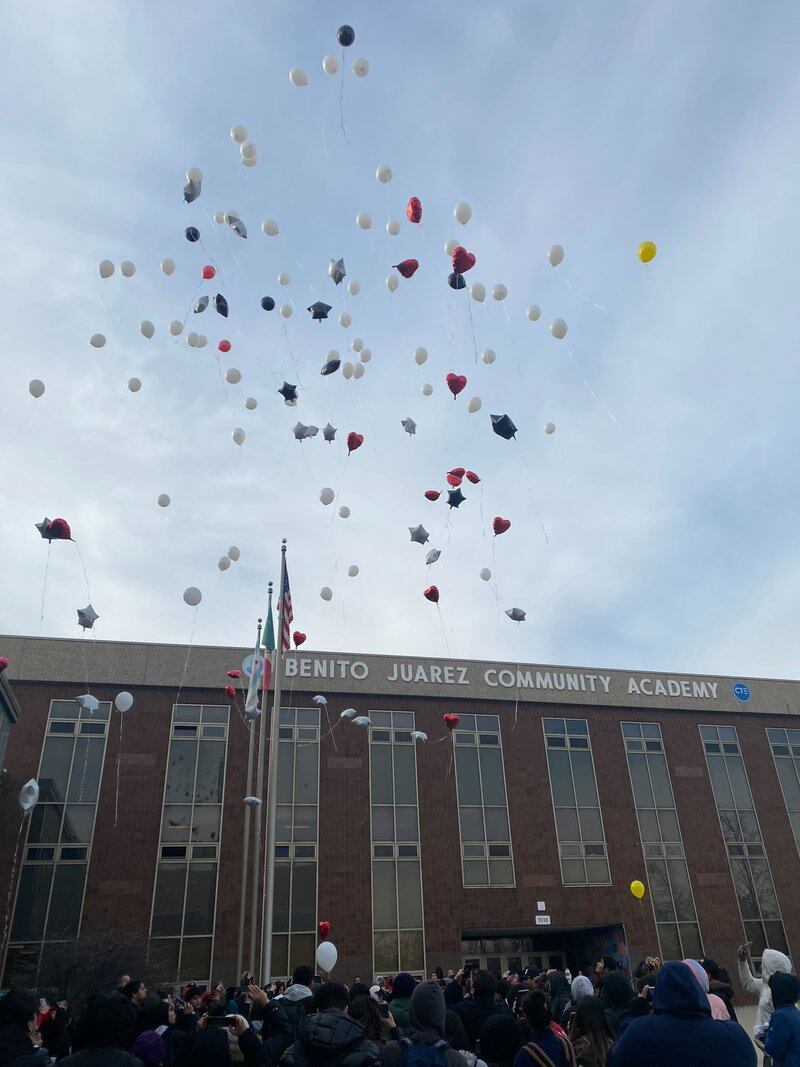 White, red, and black balloons float up to the sky outside Benito Juarez Community Academy in Chicago.