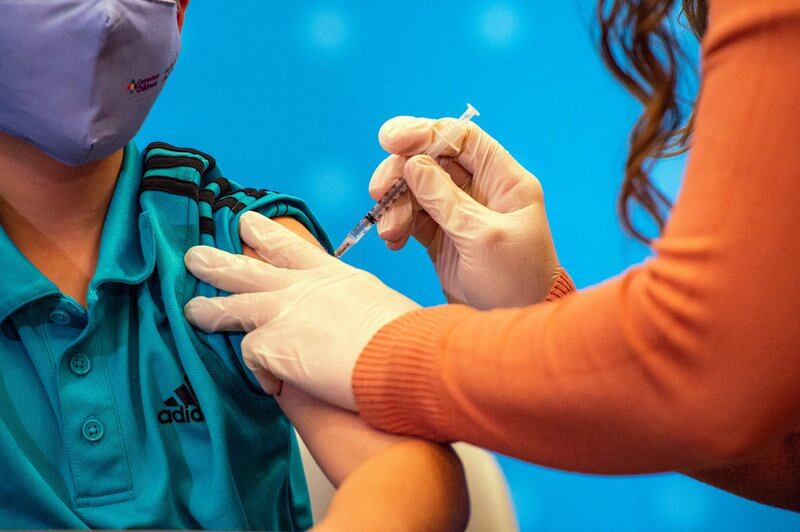 A woman healthcare worker gives a dose of the COVID vaccine to a young boy. New York City elementary schools will offer shots to children ages 5-11 next week.