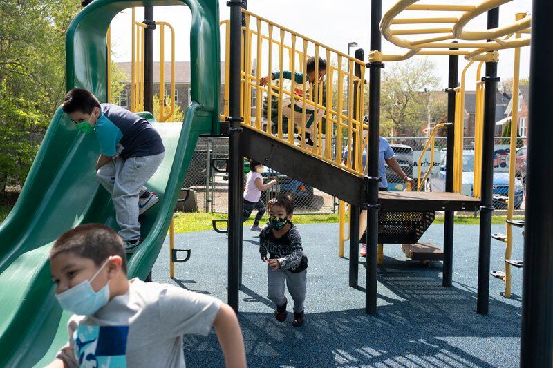Several children play on a green and yellow outdoor play structure in Chicago.