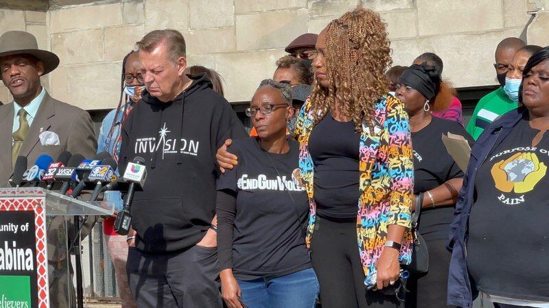 Johneece Cobb (center) is comforted by Purpose Over Pain Founder Pam Bosley as Father Michael Pfleger addresses the media during a press conference Wednesday morning. Cobb is the grandmother of the 14 year-old who was wounded in a shooting at Phillips High School in Bronzeville Tuesday.