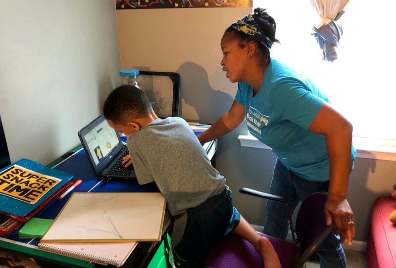 Tiffany Shelton helps her 7-year-old son, P.J. Shelton, a second grader, during an online class at their home in Norristown, Pa
