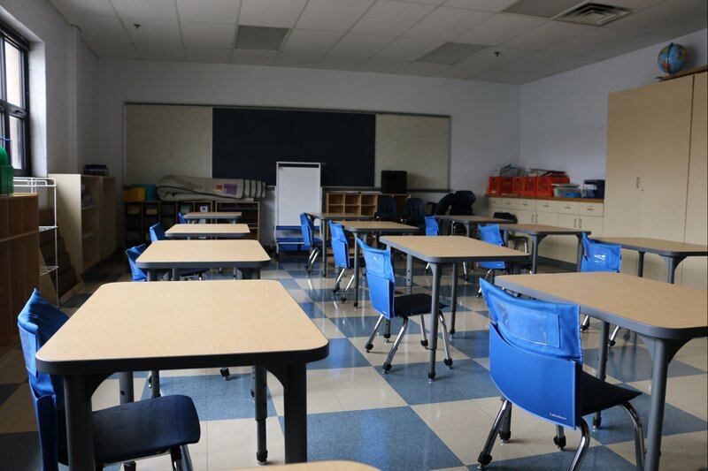A classroom with blue chairs sits empty.