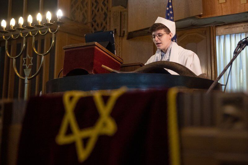 A cantor in white sings during a synagogue service. 