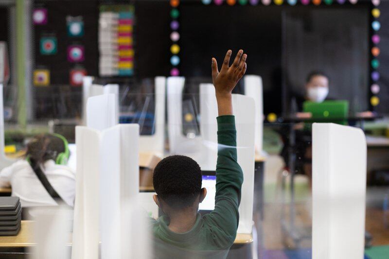 Fourth grader Christophe Afenutsu raises his hand and waits to grab the attention of his teacher Christie Kim at Roseville Community Charter School in April 2021. Recently, the Biden administration has proposed new rules on federal program designed to help launch charter schools.