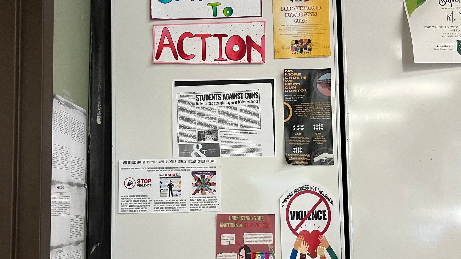 Seven signs against gun violence are affixed to a white board at Williamsburg Charter High School, including bright letters reading, “Call to Action.”