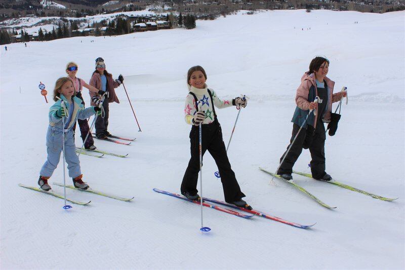 A group of children ski across a snowy landscape.