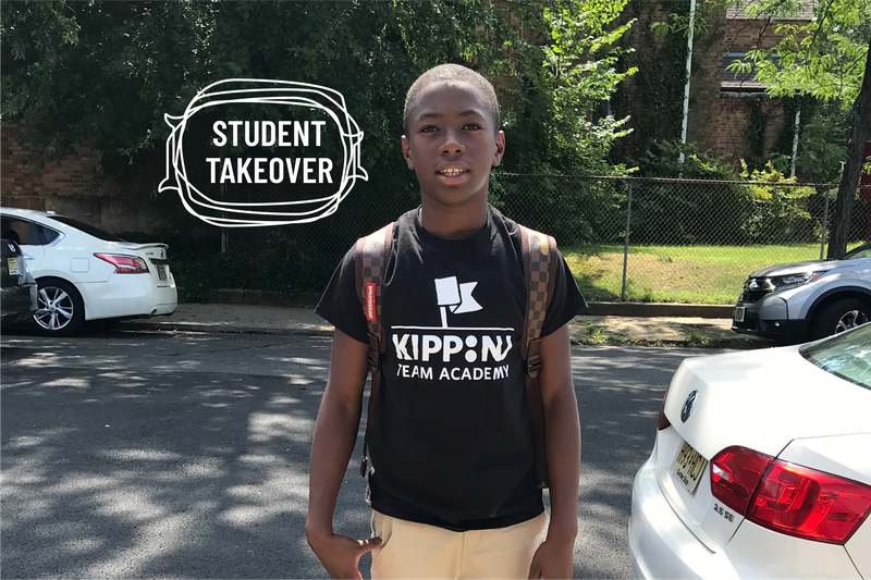 Jasin Shiggs, wearing a black KIPP Academy t-shirt and khakis, standing outside smiling.