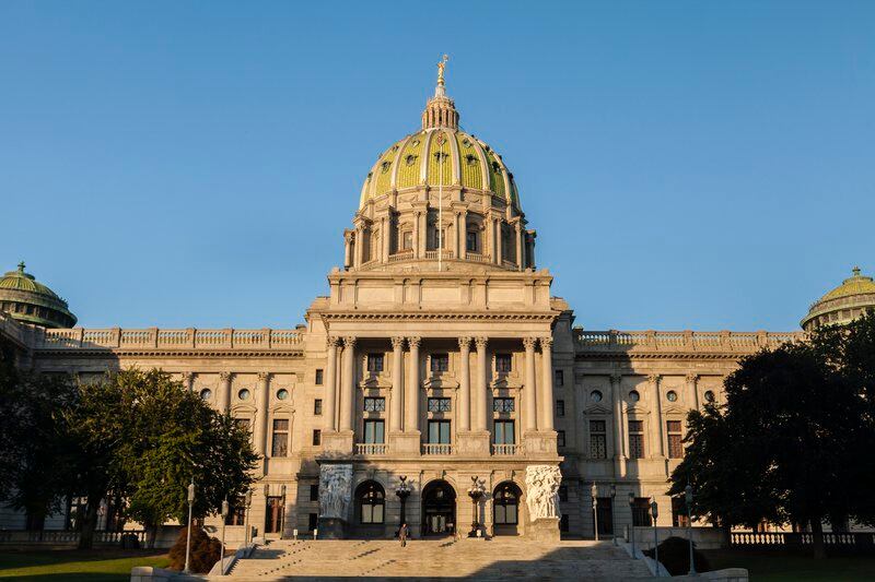 Sunlight shines on the Capitol dome in Harrisburg, Penn., with a blue sky in the background.