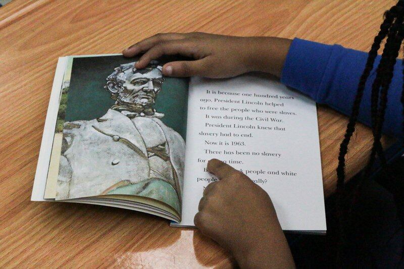 A child reads a picture book about Abraham Lincoln.