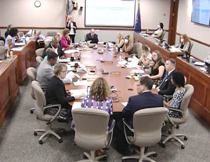 Michigan Board of Education members are joined by several other school officials seated around an oblong table in a windowless conference room in Lansing.