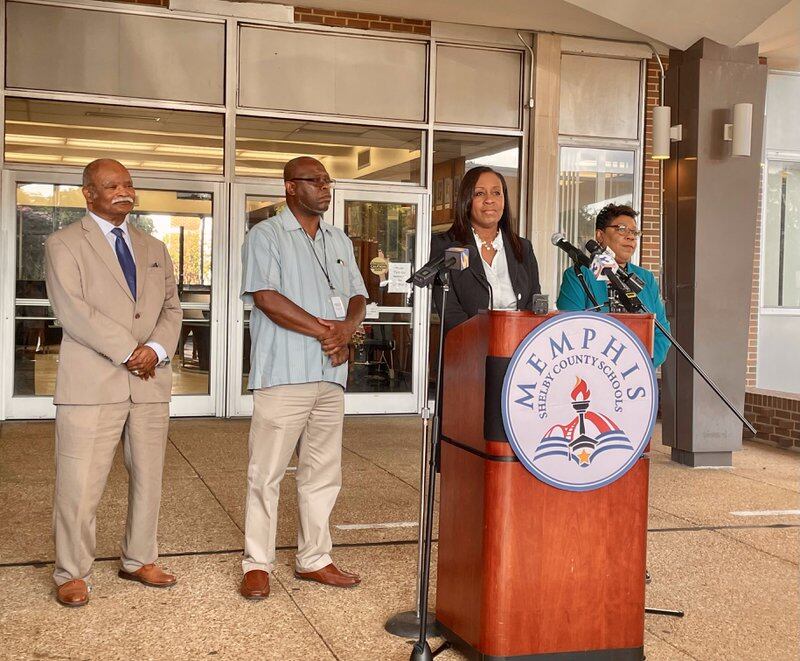 A woman stands behind a Memphis-Shelby County Schools podium next to two men and a woman