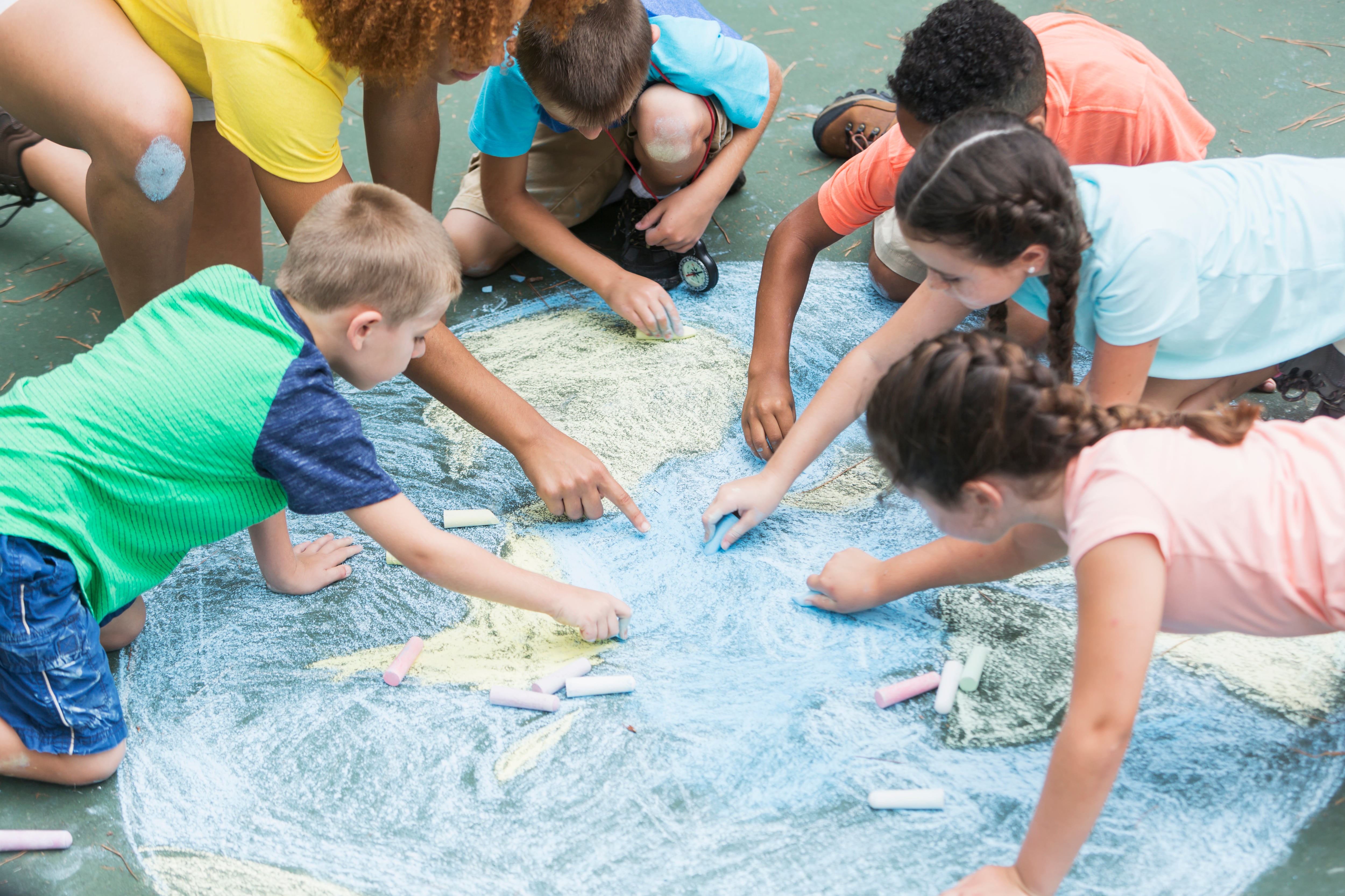 Children draw in chalk on the floor