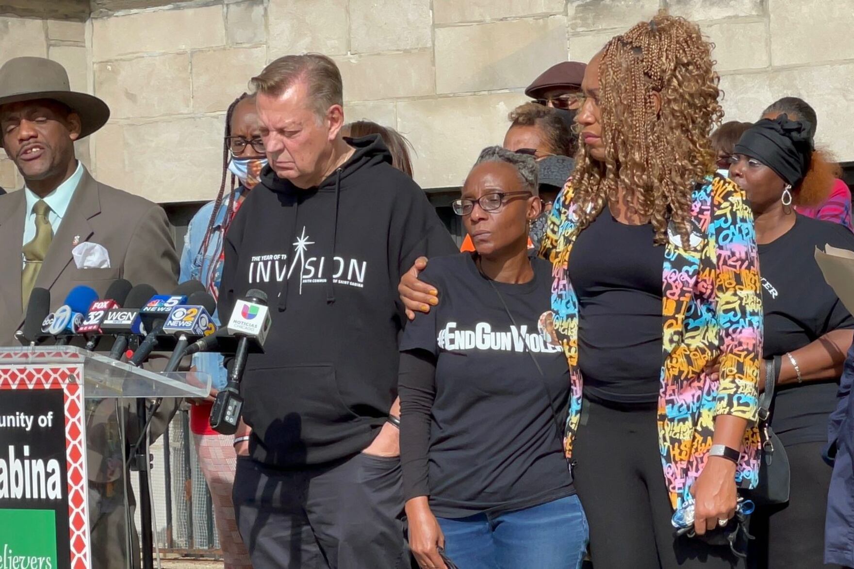 Johneece Cobb (center) is comforted by Purpose Over Pain Founder Pam Bosley as Father Michael Pfleger addresses the media during a press conference Wednesday morning. Cobb is the grandmother of the 14 year-old who was wounded in a shooting at Phillips High School in Bronzeville Tuesday.