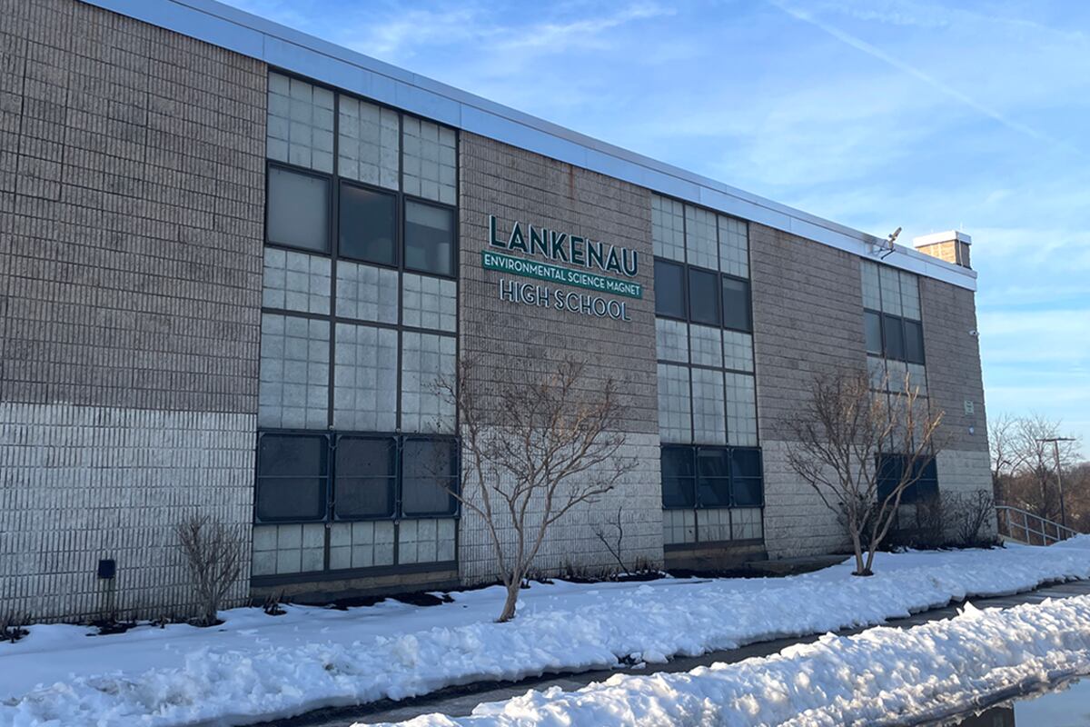 A building sign hangs outside a brick building.