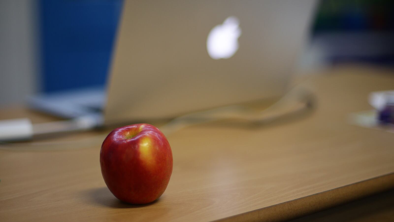 An apple next to an Apple laptop on a teacher's desk