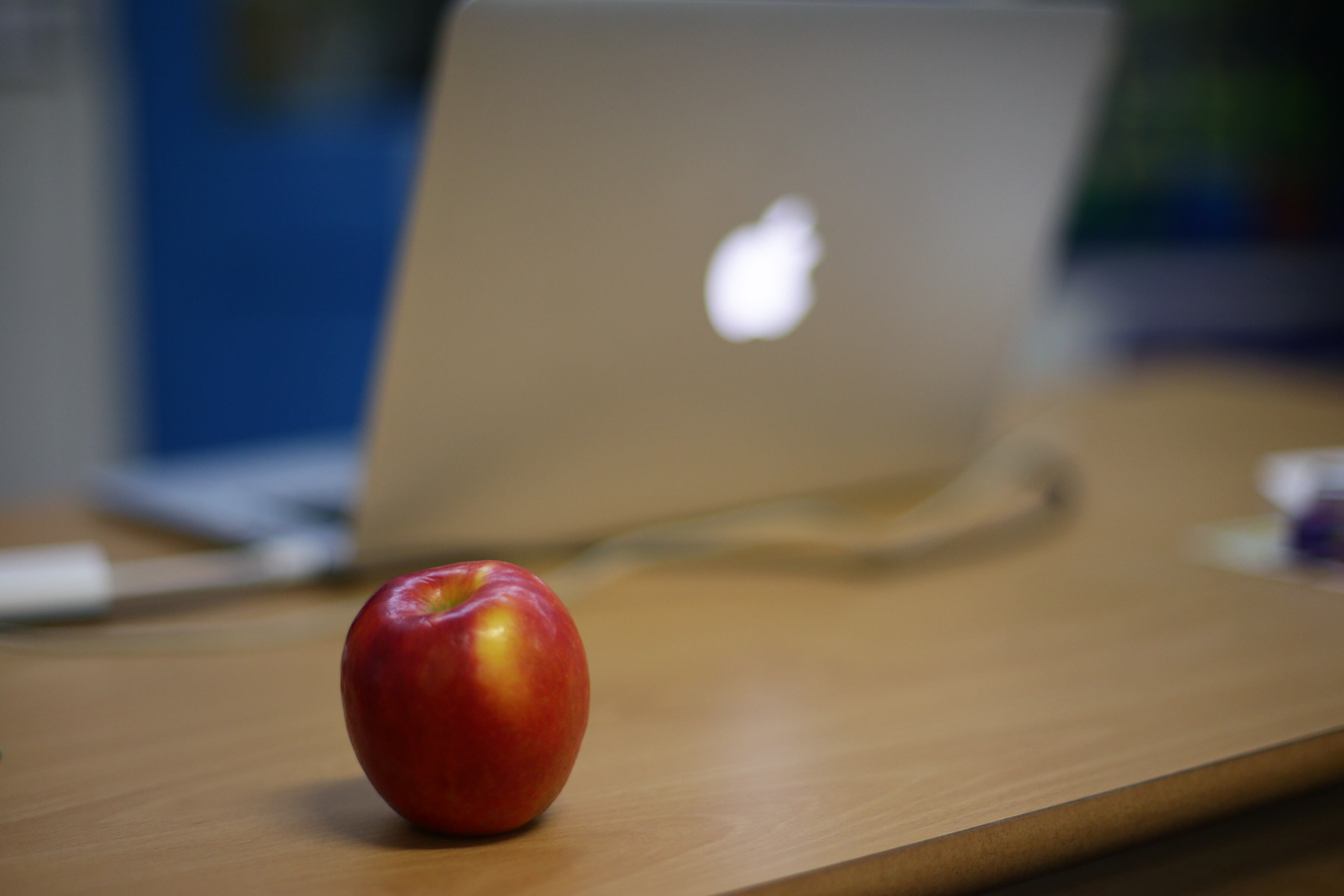 An apple next to an Apple laptop on a teacher's desk