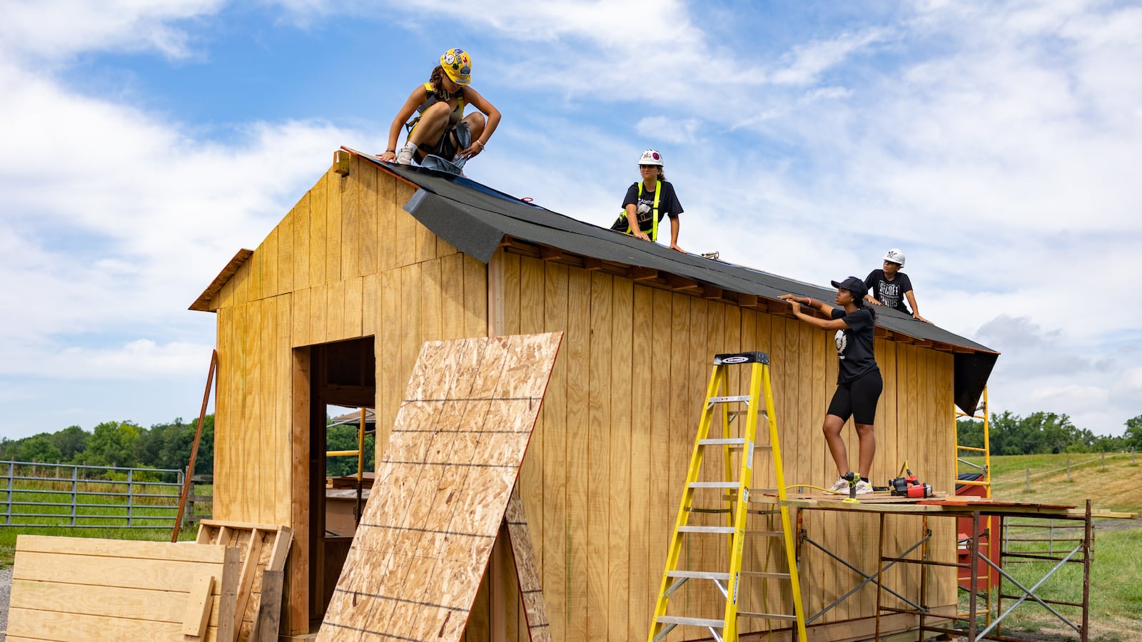 Students work on constructing a shed outside on a farm.