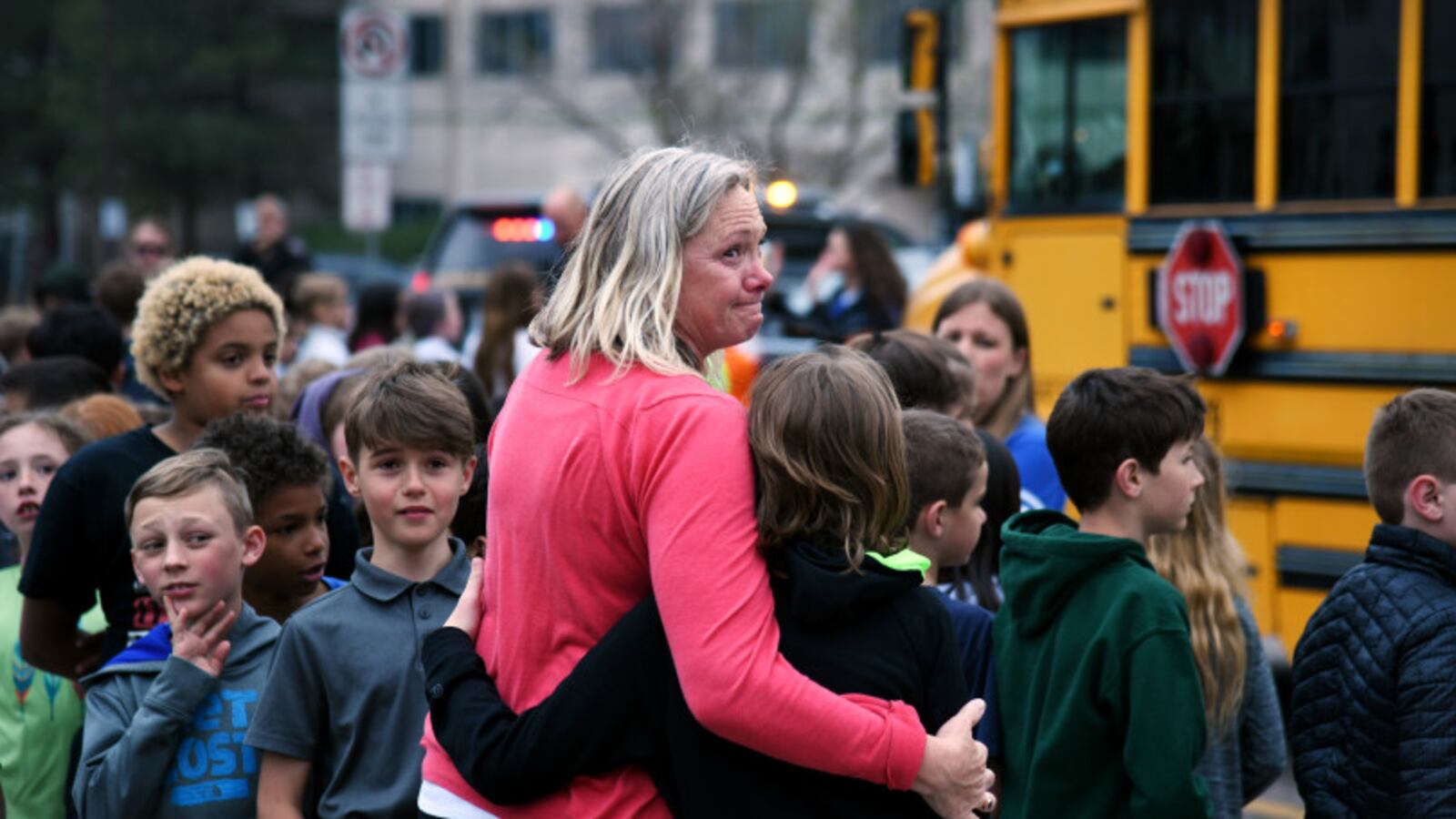 Melanie Fitzroy, an AM Elementary EA, embraces a child as students wait to be escorted to buses as they are evacuated from STEM School Highlands Ranch after a school shooting.