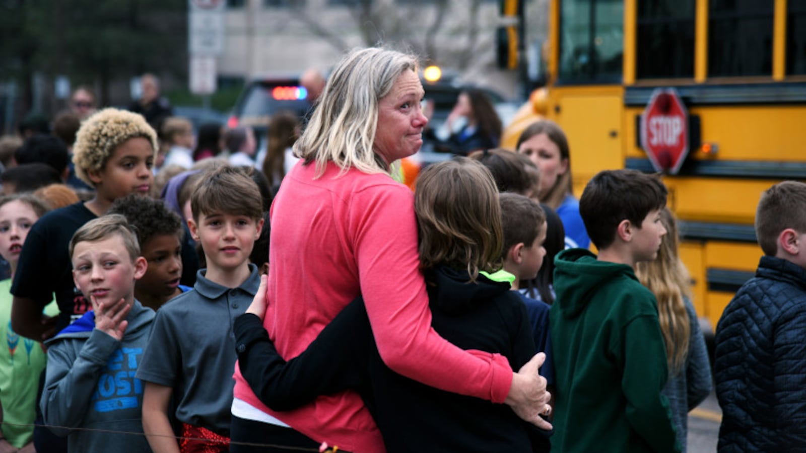 Melanie Fitzroy, an AM Elementary EA, embraces a child as students wait to be escorted to buses as they are evacuated from STEM School Highlands Ranch after a school shooting.