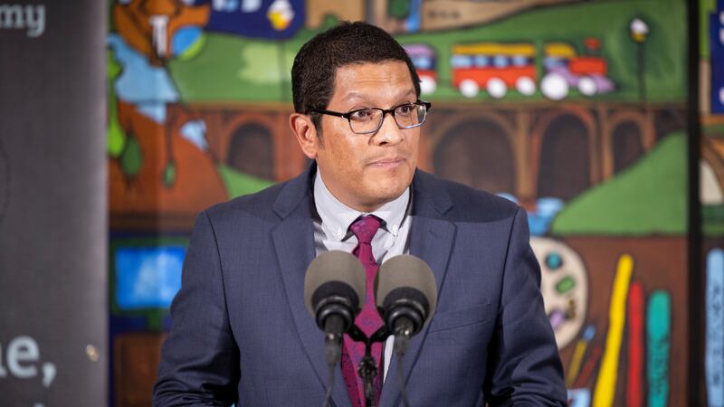 Standing in front of a colorful mural, Pennsylvania secretary of education Noe Ortega answers questions during a press conference.