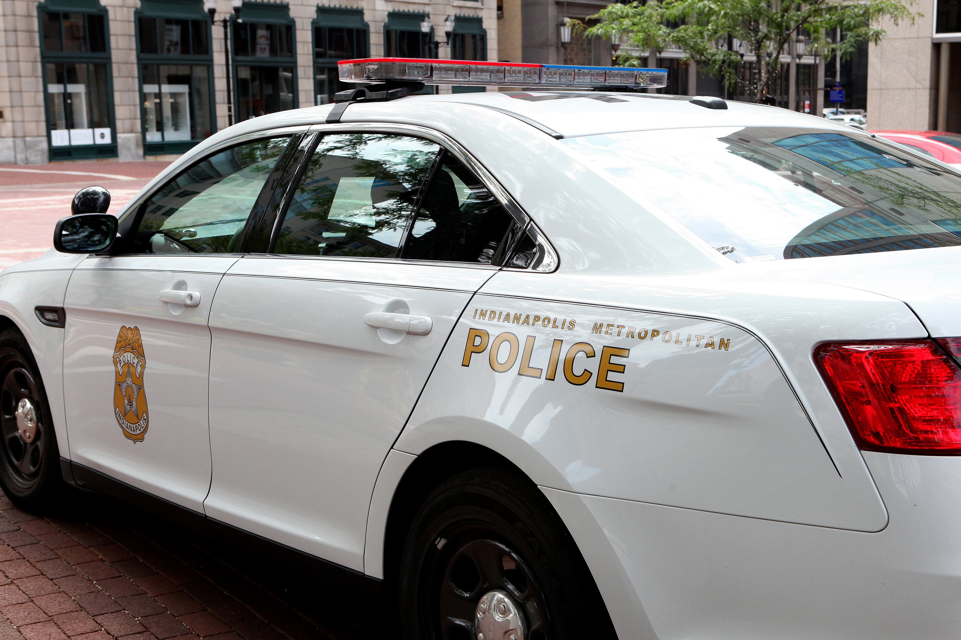 A white police car is parked on a red brick road.