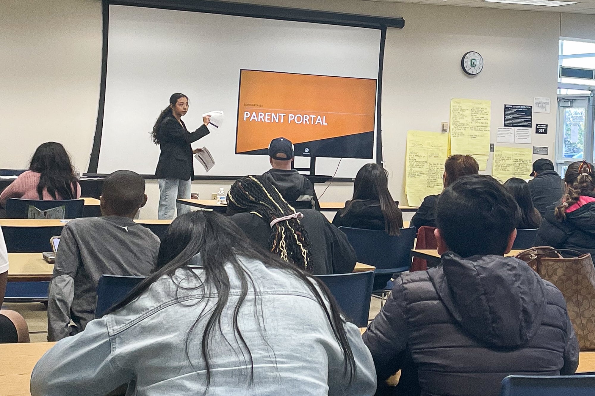 woman speaks to people sitting at desks