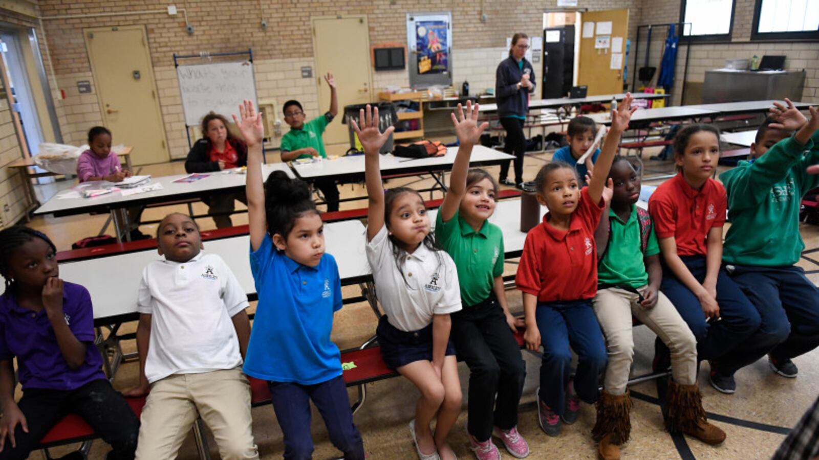 Aliyah Biggs, 6, second from left and Ashli Ramos-Rosales, 8, raise their hands to take part in an after-school talent show at Ashley Elementary in Denver.