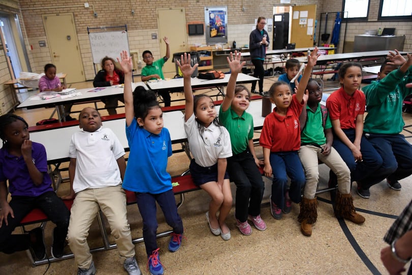 Aliyah Biggs, 6, second from left and Ashli Ramos-Rosales, 8, raise their hands to take part in an after-school talent show at Ashley Elementary in Denver.
