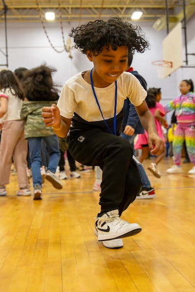 A young student kicks up their foot while dancing at an event celebrating good school attendance.