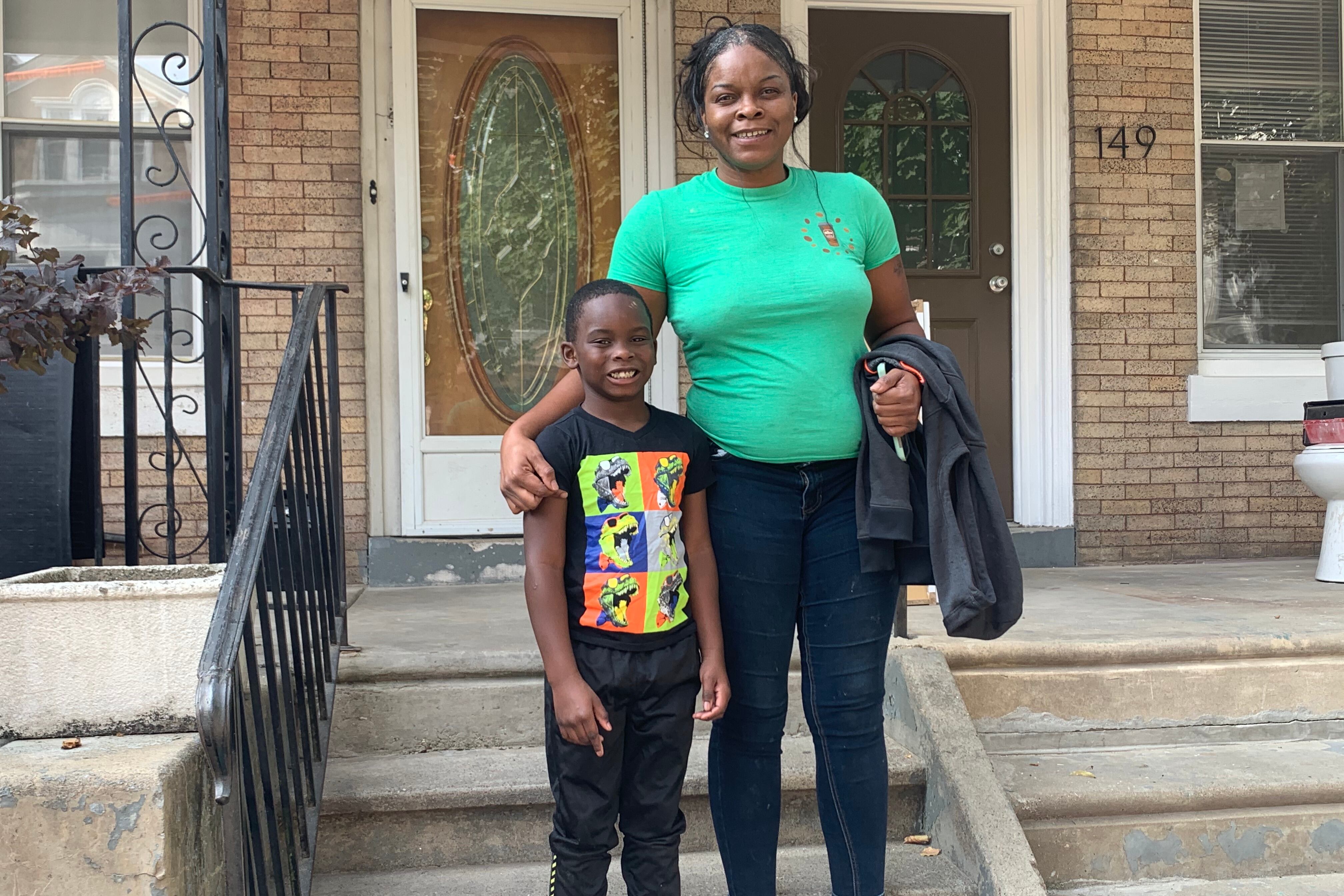 Ashley Chalmers and son Zion in front of their home.