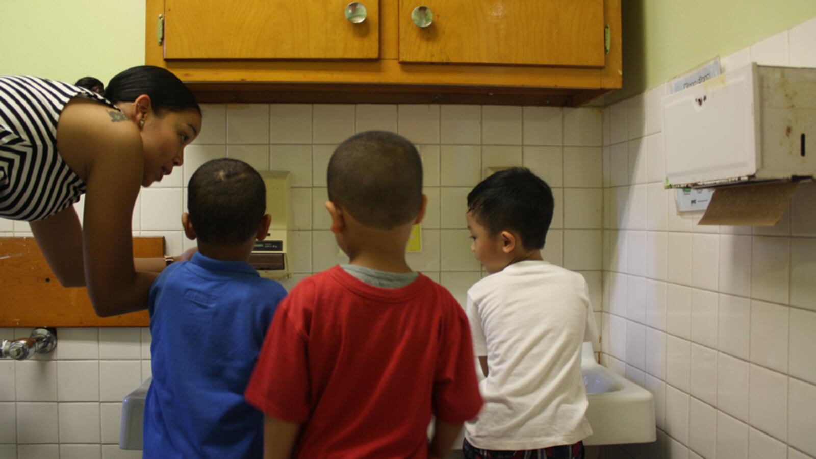 Pre-K teacher Khadija Prowell shows students how to wash their hands on the first day of school at Grand Street Settlement.