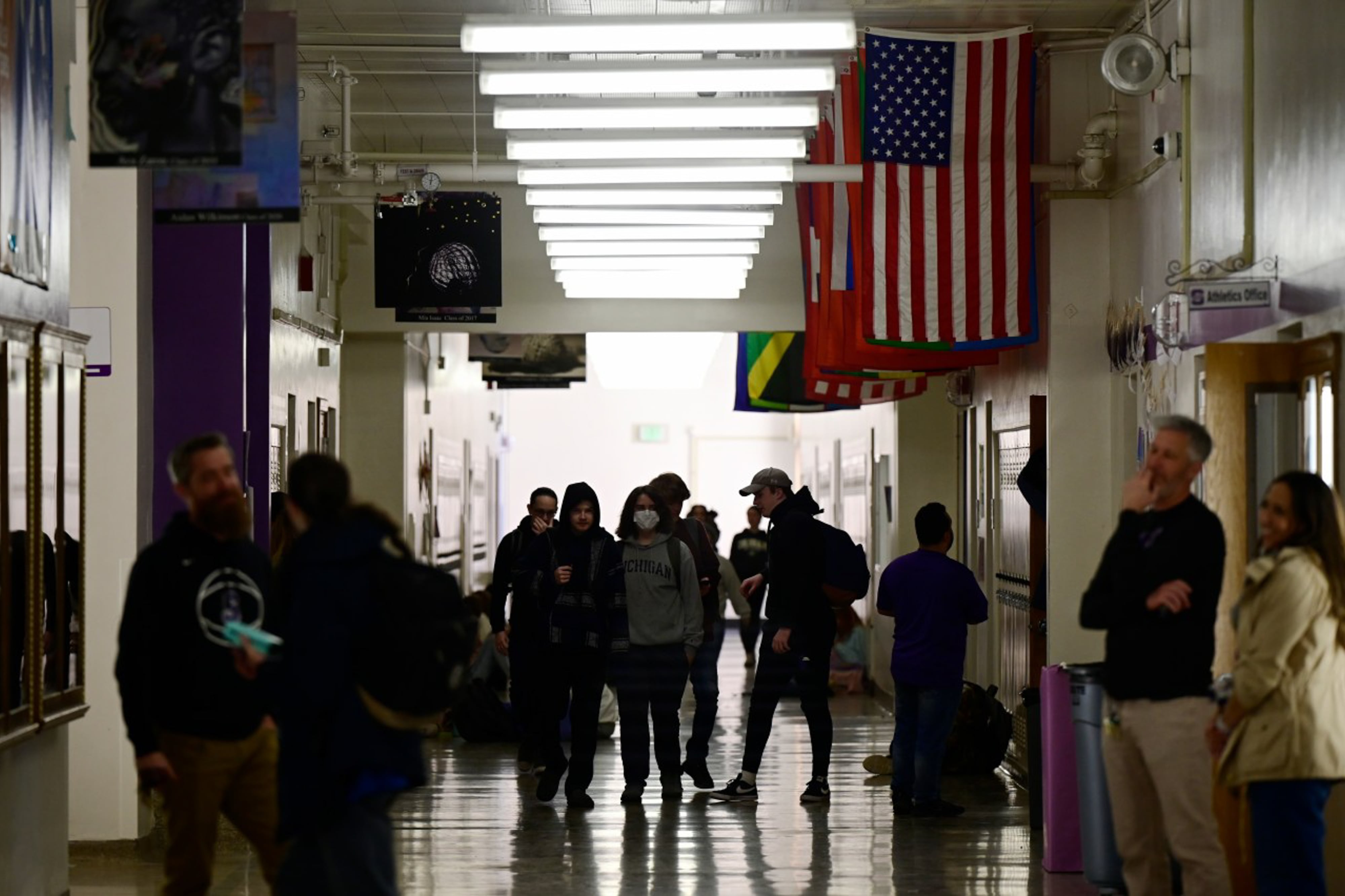 High school students walk in a darkened hallway that has flags hanging from the ceiling.