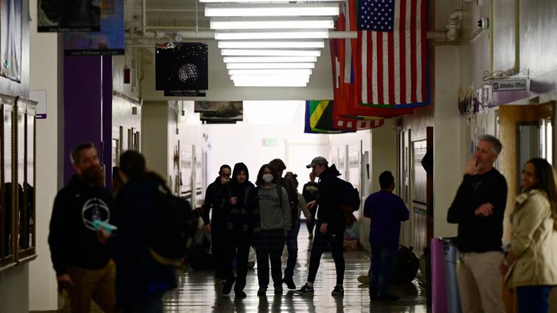 High school students walk in a darkened hallway that has flags hanging from the ceiling.