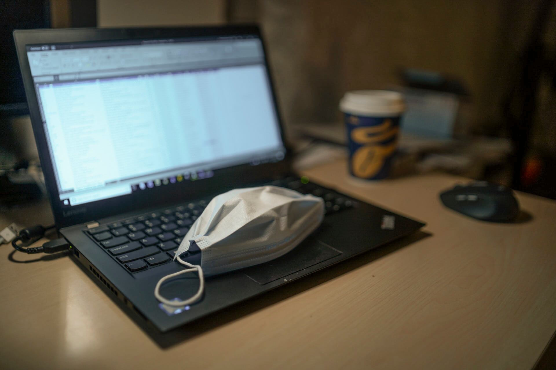 A protective face mask resting on the keyboard of a laptop computer.