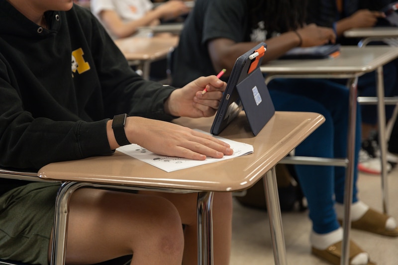 A student works at their desk on a tablet.