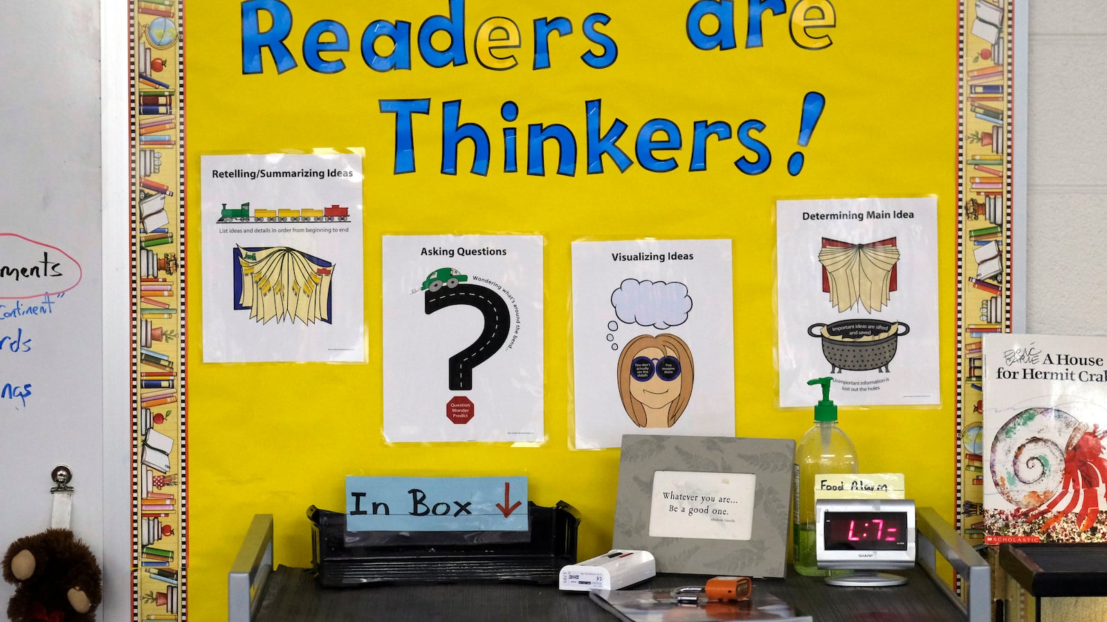 A yellow wall says “Readers are Thinkers!” in blue lettering. On the wall, are pieces of laminated paper that has pictures and words.