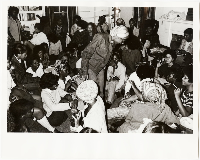 A black and white photograph of a large group of Black students gathering in a room.